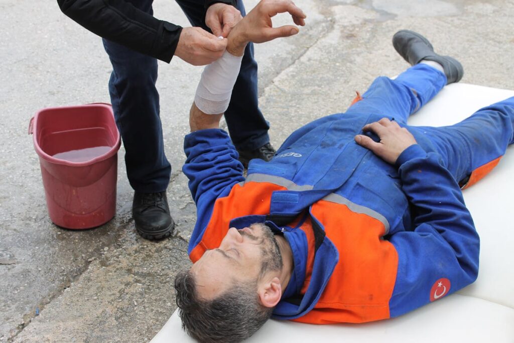 Injured Man lying on the Ground receiving a First Aid Treatment